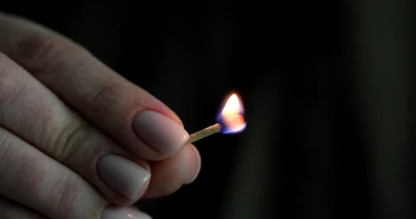 Woman hand holds burning match on black background. Burning match in hand closeup in evening