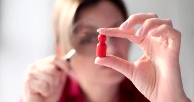 Woman rector looks at a wooden man through magnifying glass. Recruitment concept talented employees and promotion