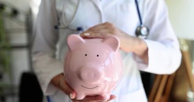 Domuzcuk bankasında doktordan tıbbi bakım parası. Doktor terapist domuz kumbarası tutuyor.