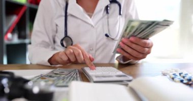 Doctor therapist counts money in medical clinic with calculator. Corruption cost concept of health care and health insurance