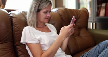 Smiling woman is using mobile phone and looking at smartphone screen. Chatting with friends