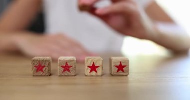 Woman hand puts wooden cube with recall star symbol. Providing feedback and rating of services and goods