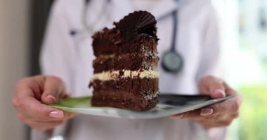 Beslenme uzmanı elinde tatlı çikolatalı pasta tutuyor ve şekerlerin tehlikeleri hakkında uyarıyor. Doktor kozmetolog ve şekerin cilt üzerindeki etkisi