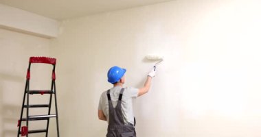 Painting walls with roller in white. Apartment renovation and painter paints the walls