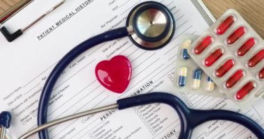 The pink heart is a blue stethoscope and tablets on the table, a close-up. Treatment of cardiovascular disease