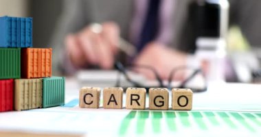 Cargo inscription on wooden cubes on the table, close-up, shallow focus. Transport company, container delivery