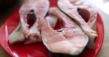 Salmon, pink raw fish steaks lie on a red plate, closeup, slowmotion. Mediterranean diet, omega3, cooking