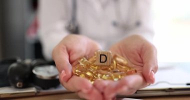 Yellow capsules of vitamin D3 in the hands of a doctor, close-up. Healthy nutrition, body support, slowmotion