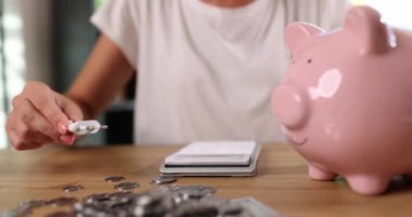 Hands connect an electric cable to the piggy bank, close-up, slowmotion. Alternative energy, saving electricity