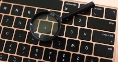 Büyüteç bir bilgisayar klavyesinde duruyor, yakın çekim, yükseltilmiş görüntü. Kişisel veri hırsızlığı, hackleme