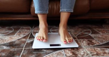 Female legs in jeans stand on electronic scales, close-up. Diet control. Weight measurement concept