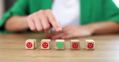 On the table in a row, wooden cubes with emotions, a close-up, slowmotion. A woman chooses positive