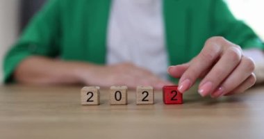 On the table in a row, wooden cubes with a date 2022 2023, close-up. A woman changes the number and calendar