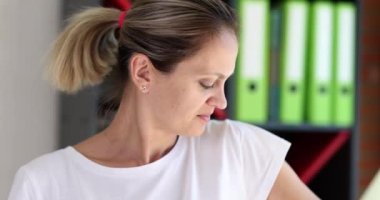 A young woman in a white tank top sniffs her armpit, close-up, slowmotion. Bad smell of sweat, dirty body