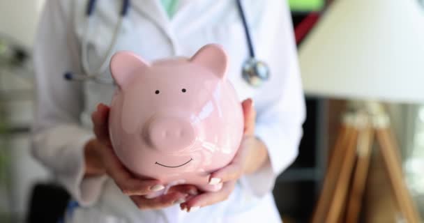 Doctor Standing Clinic Holds Pink Piggy Bank Close Slowmotion Medical — Stock Video