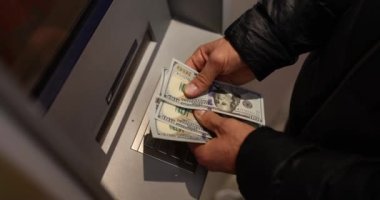 Male hands count dollars at the ATM, a close-up, slowmotion. Cash withdrawal from your account