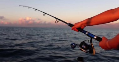 Young female hands at sea with a fishing rod, close-up. Beautiful view of nature, hobby to catch fish