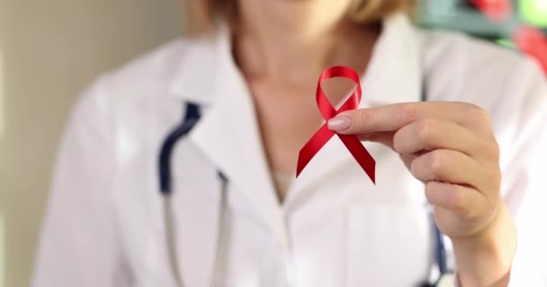 診療所の医師は 赤いサテンリボン クローズアップを示しています 乳がんとの闘いの象徴 — ストック動画