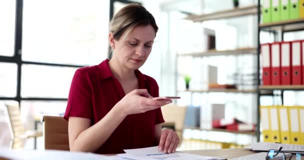 사무직 여성은 사무실 슬로우 모션에서 전화로 문서를 촬영했다 — 비디오