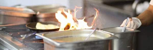 Cooking in the kitchen in restaurant on fire. Cafe chef preparing dishes on fire