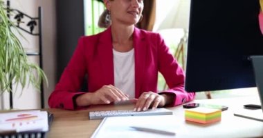 Businesswoman sitting in front of computer and waving her hand at camera 4k movie slow motion. Professional business consulting concept