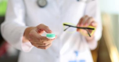 Doctor ophthalmologist holding eyeglasses and contact lenses in hands closeup 4k movie slow motion. Vision correction concept