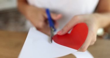 Woman cutting out of paper red heart with scissors closeup 4k movie slow motion. Valentine day cards concept