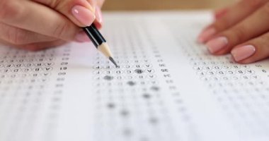 Student solving tests and crossing out correct answers with pencil on paper closeup 4k movie slow motion. Exam testing concept