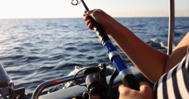 Fisherman sailing on boat and catching fish with fishing rod closeup 4k movie slow motion. Hobby fishing concept