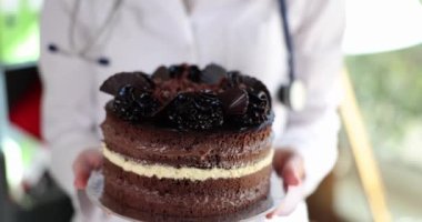 Doctor nutritionist holding in hands delicious appetizing cake closeup 4k movie slow motion. Medical worker day concept