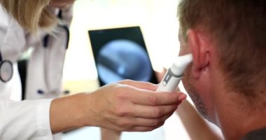Doctor otorhinolaryngologist examining patient with otoscope on digital tablet closeup 4k movie slow motion. Diagnosis and treatment of hearing loss concept