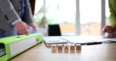 Words trade on wooden cubes on background of business people handshake 4k movie slow motion. Business deal concept