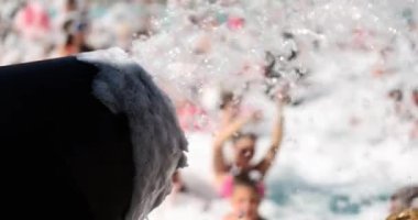 Sabun köpükleri toptan yüzme havuzuna uçuyor ve insanlar 4K 'lık filmi yavaş çekimde çekiyorlar. Spa köpük partisi konsepti