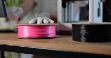 Worker unwinding spool of plastic for 3d printer closeup 4k movie slow motion. Manufacturing and robotic automation technology concept