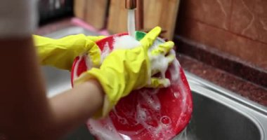 Lastik eldivenli ev hanımı bulaşıkları süngerle yıkıyor ve deterjanı kapatıyordu. 4k film yavaş çekimdi. Rutin ev işi kavramı