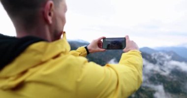 Erkek gezgin cep telefonu dağlarında fotoğraf çekiyor. 4K yavaş çekim. Doğa konseptini fotoğraflama hobisi