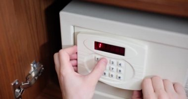 Male hand typing password on door of metal safe on door in hotel closeup 4k movie slow motion. Storage of valuables concept