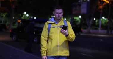 Kafası karışmış turist şehirde bir adres arıyor. Cep telefonu 4K yavaş çekim kullanıyor. Yer belirleme mobil uygulama kavramı