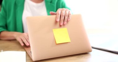 Office worker finishes working day by closing lid of laptop. End of the working day