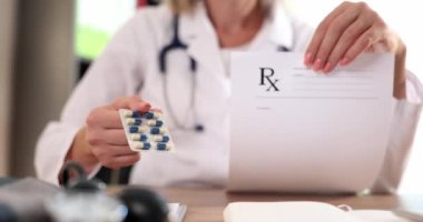 Doctor hands over prescription and holds blister of pills in hands. Getting prescription for medicines in the concept of medical institution