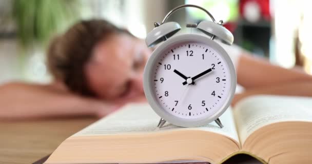本を読んだ後 目覚まし時計の若い女性が眠っている 疲労過労と教育 — ストック動画