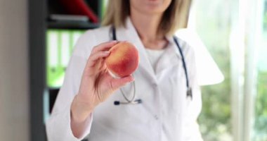 Nutritionist holds beautiful healthy peach in hand. Healthy food diet and vitamins