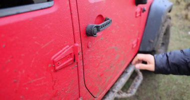 Extreme driver opens door of red SUV. Off-road racing 4x4