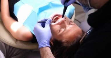 Woman treating teeth in dentist office. Dental services and oral care concept