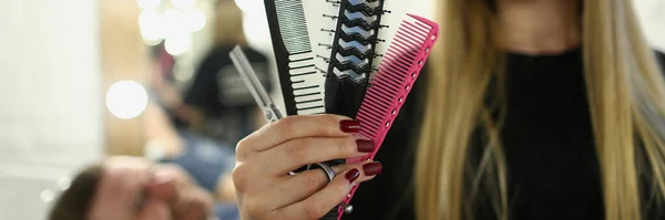 Hairdresser woman holding comb and scissors in barbershop. Men stylish haircuts concept