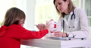 Child girl looks at anatomy of eye at ophthalmologist doctor. Myopia in children causes symptoms diagnosis