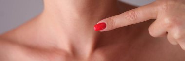 Young woman pointing her finger at neck. Thyroid disease concept