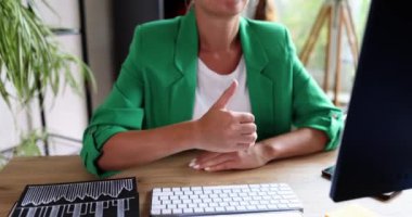 Business woman with thumbs up in office with computer. Successful business recommendation and good reviews