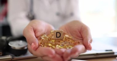 Dietician therapist hands holding many vitamin D capsules. Vitamin D analysis and daily intake