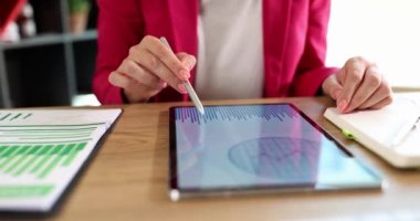 Analyst woman hand pointing at the screen of tablet with chart. Business planning and financial analytics with statistics